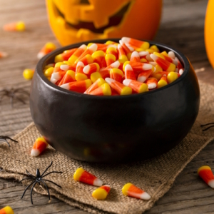 bowl with candy corn next to a pumpkin